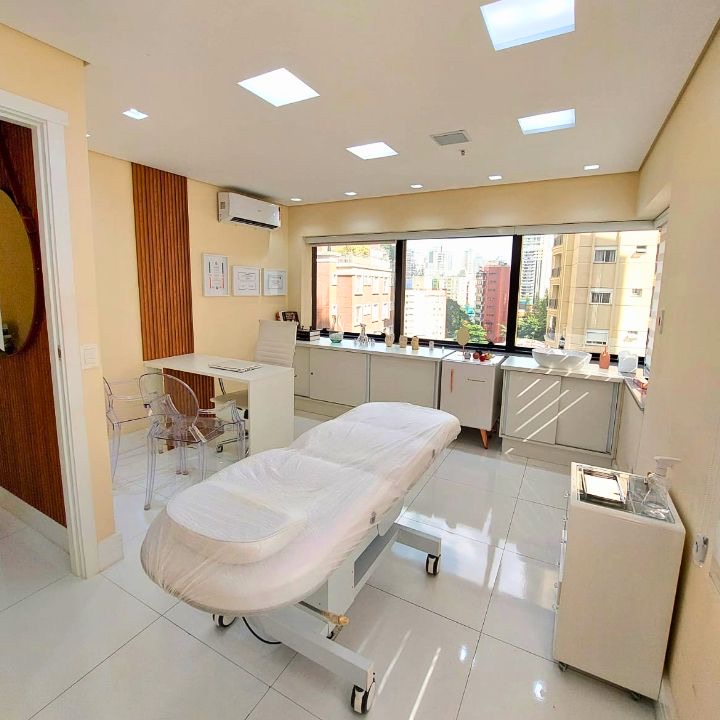 Sala de atendimento da clínica, com maca e janela para a Vila Nova Conceição